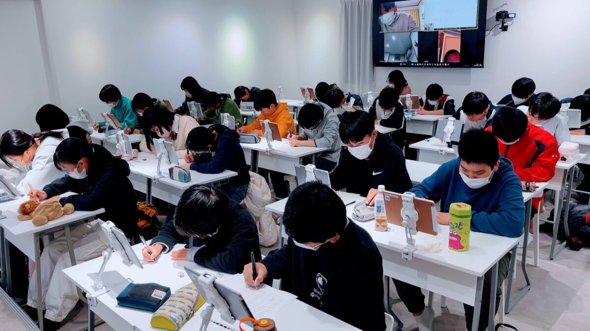 机に向かって書き取りの練習をする生徒たち