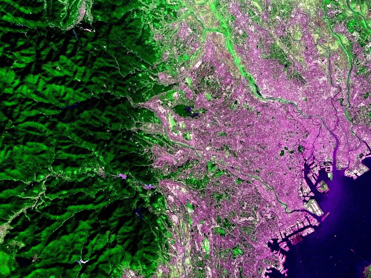 宇宙から見下ろした東京と東京湾。左の山地は濃い緑、右の街はむらさき色に写っている