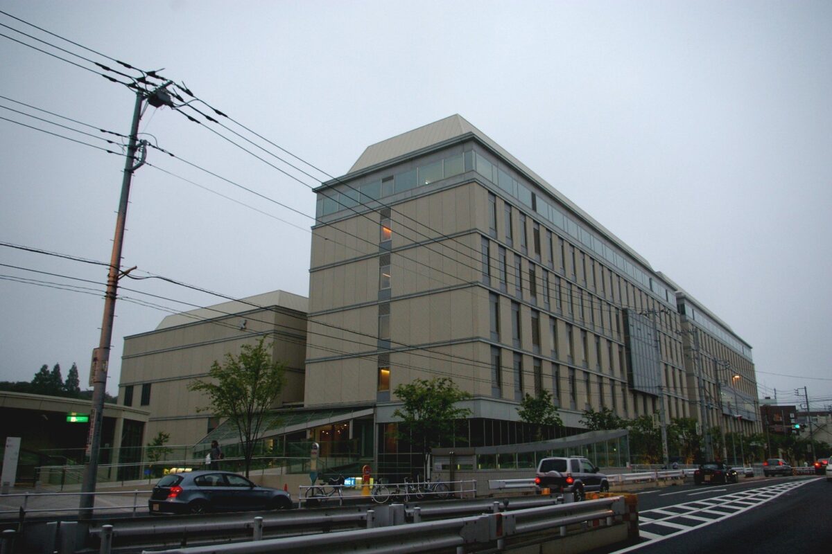 道路ぞいに建つ、ベージュの壁の大きな建物