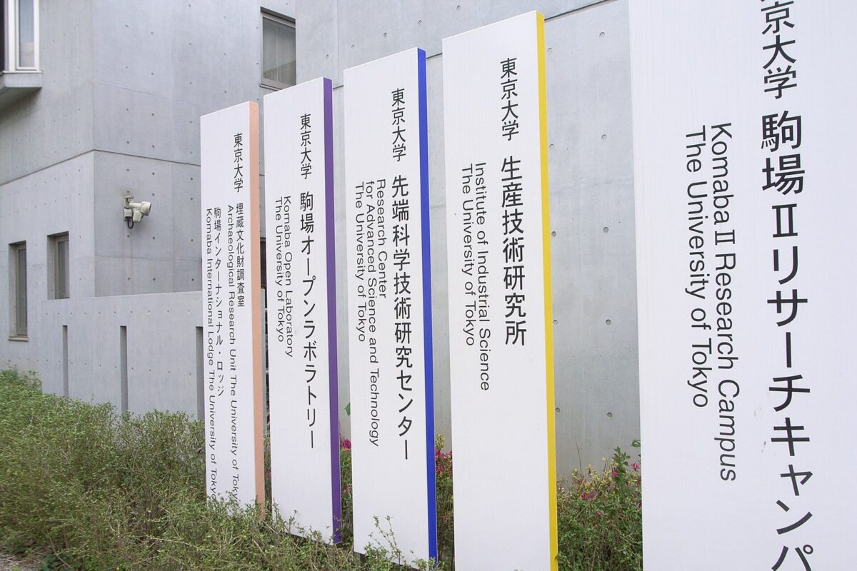 コンクリートの建物の前に、東京大学 駒場IIリサーチキャンパス、先端科学技術研究センター、生産技術研究所などと書かれた白い縦長の看板が並んでいる