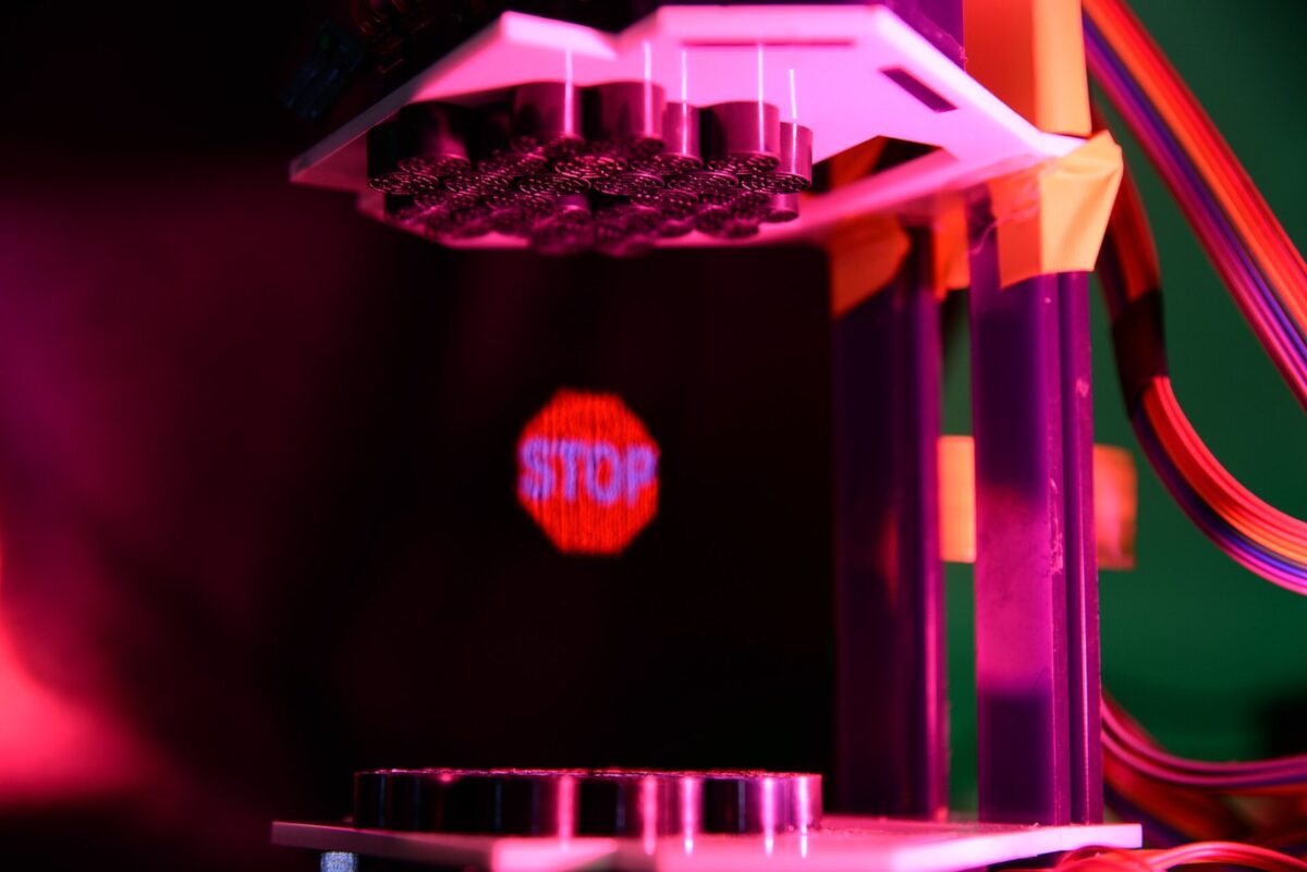 上と下に小さなスピーカーを並べた装置のあいだの空中に、赤い一時停止の標識「STOP」が光で浮かんでいる