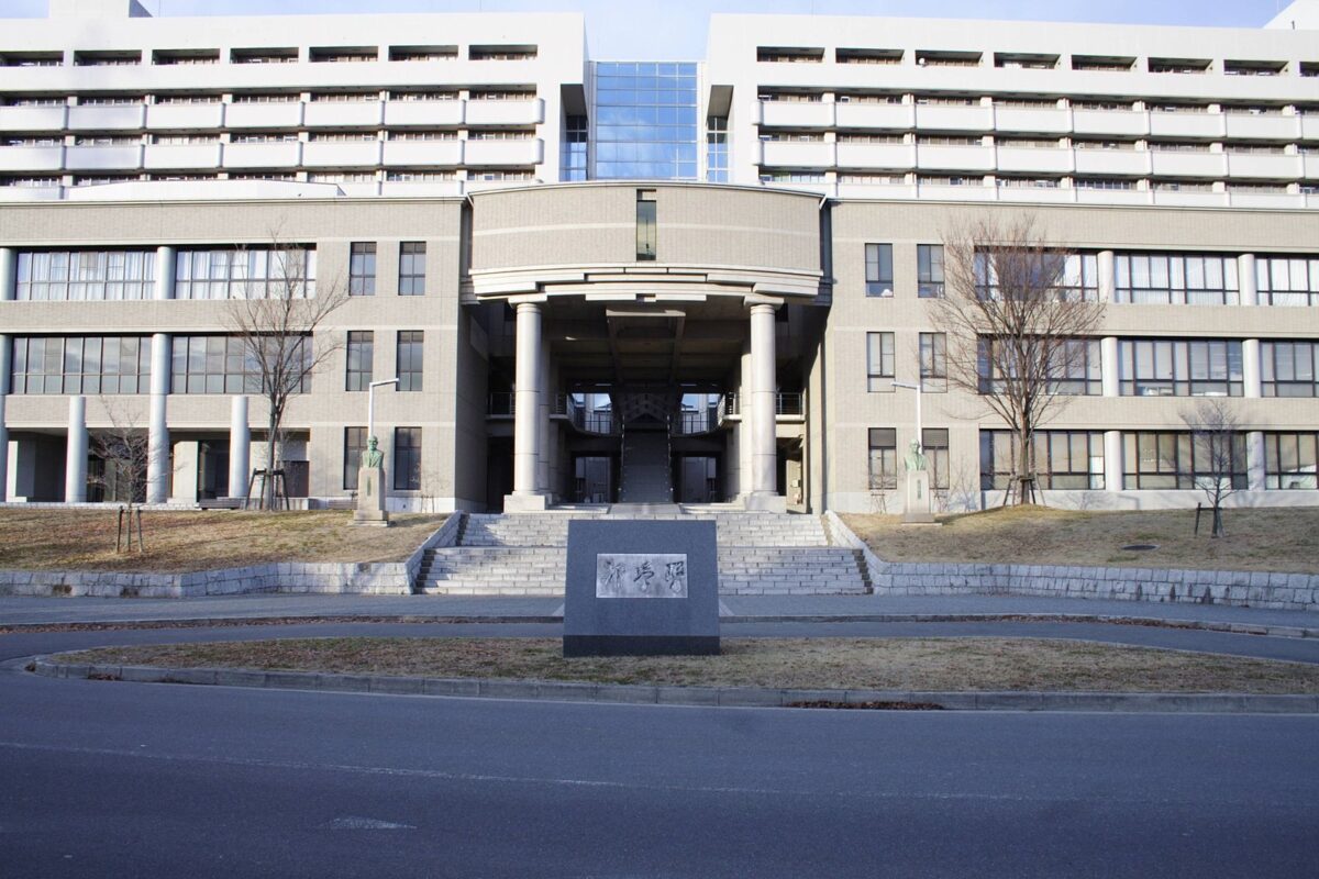 柱の並んだ玄関と広い階段がある、白い壁の大きな大学の建物
