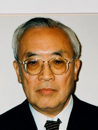 眼鏡をかけ、背広にネクタイ姿の年配の男性の肖像写真