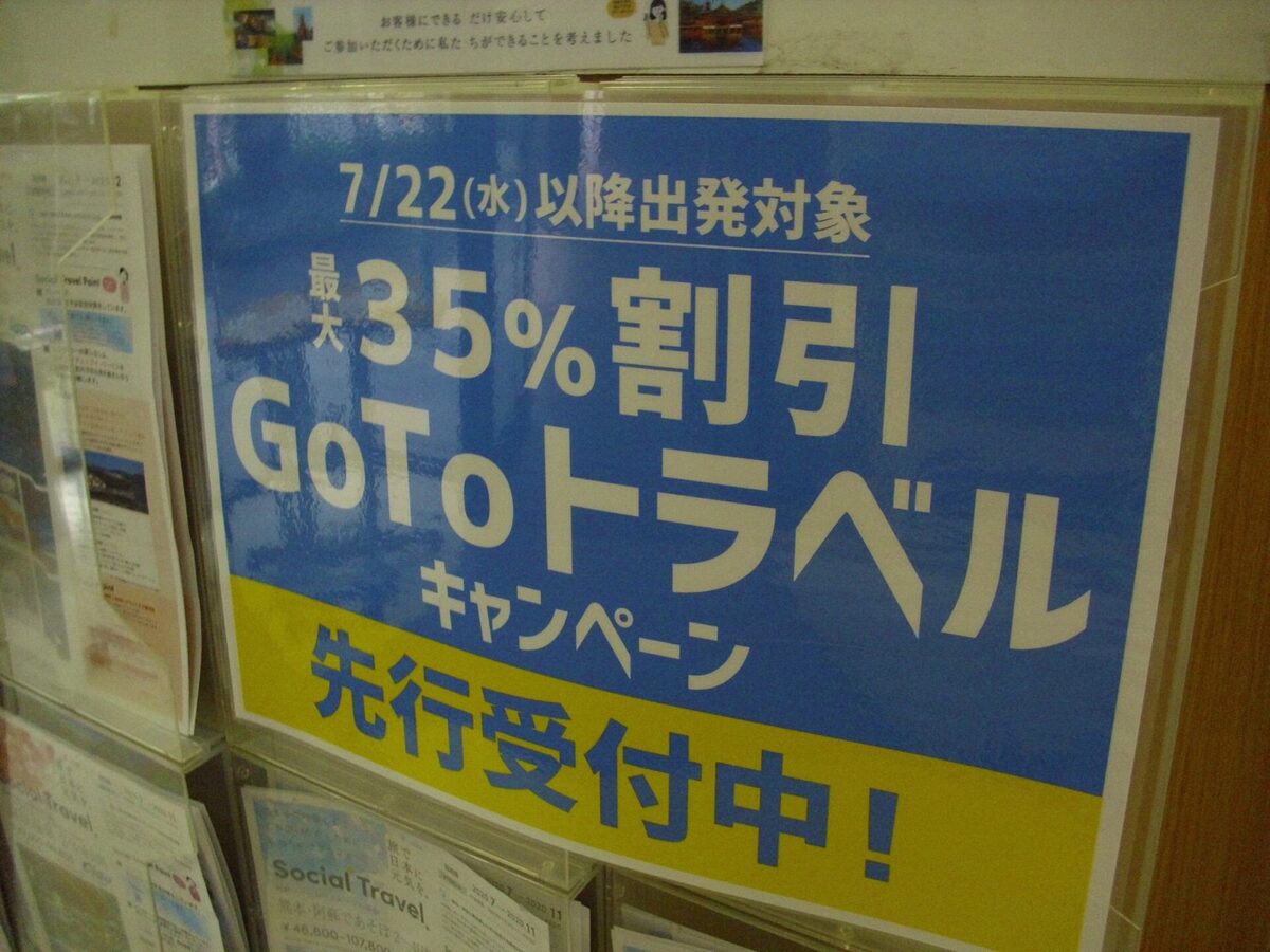 旅行のパンフレットが並ぶ棚に貼られた、「最大35%割引 GoToトラベルキャンペーン 先行受付中!」と書かれた青と黄色の張り紙