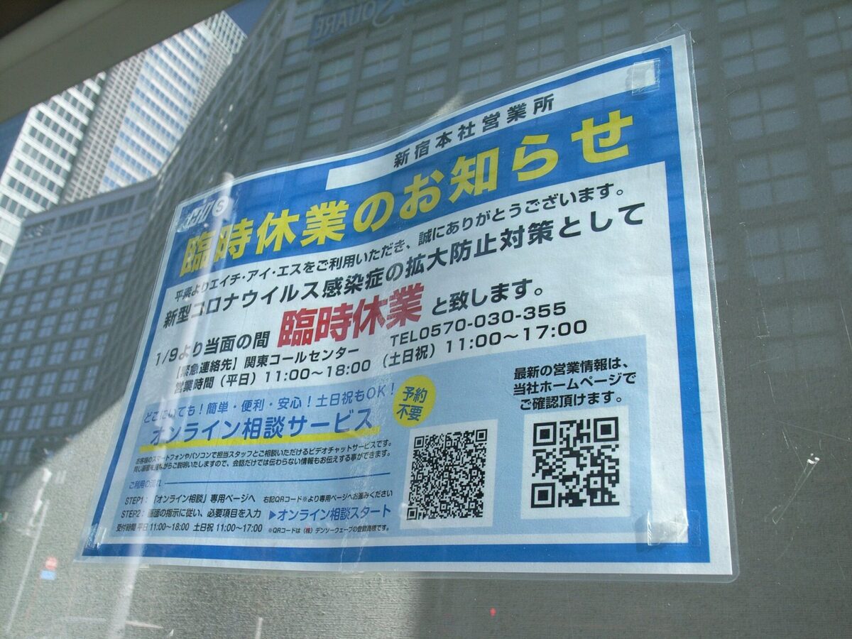 店のガラス窓に貼られた「臨時休業のお知らせ」の張り紙。新型コロナウイルスの感染拡大を防ぐため当面の間休業すると書かれ、窓に高いビルが映っている