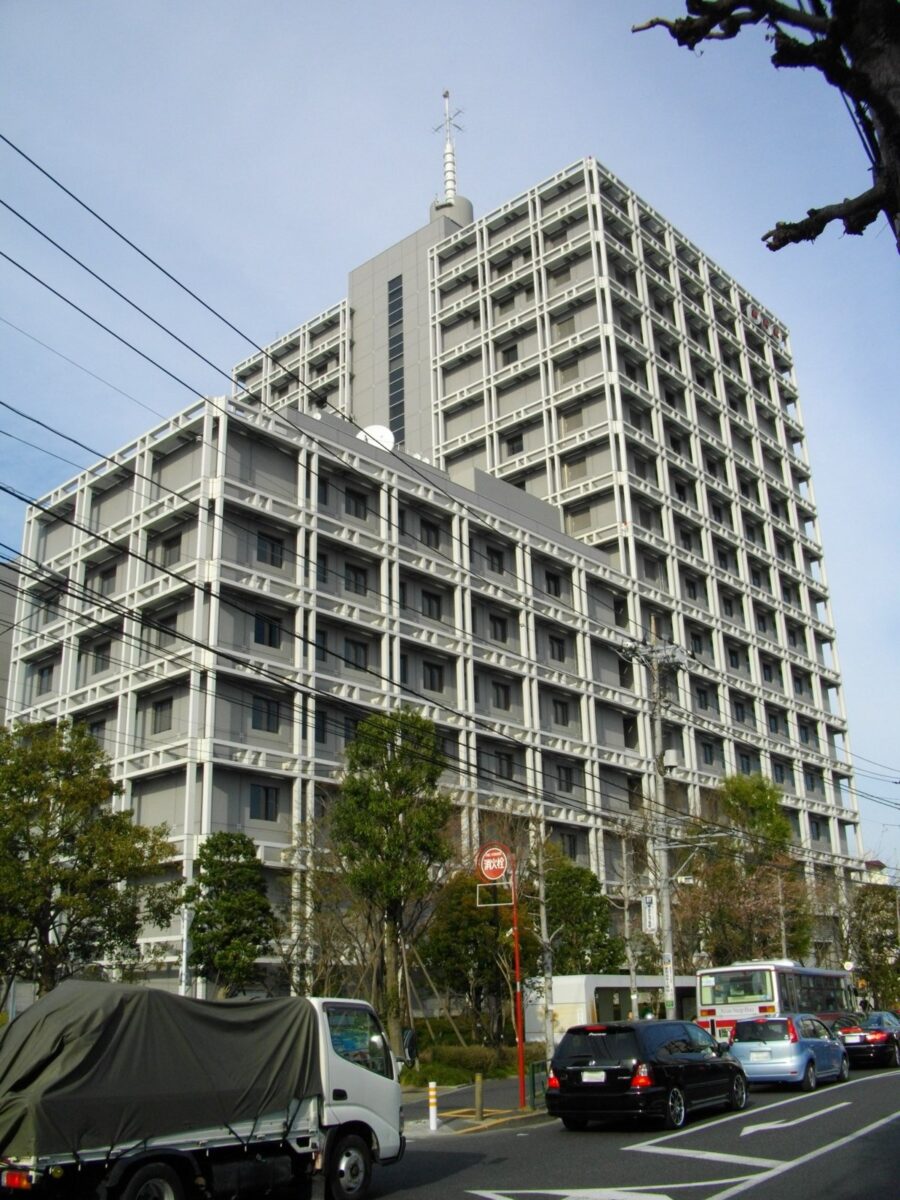 大きな通り沿いに建つ、白い格子の窓が並ぶNHK放送技術研究所の高い建物
