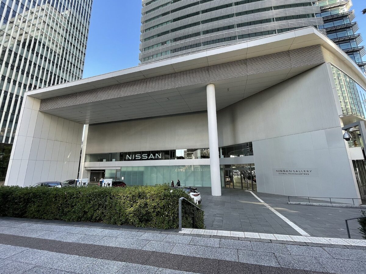 高いビルの足元に、白く大きな屋根の入り口がある。ガラスの上に「NISSAN」、右の壁に「NISSAN GALLERY GLOBAL HEADQUARTERS」の文字