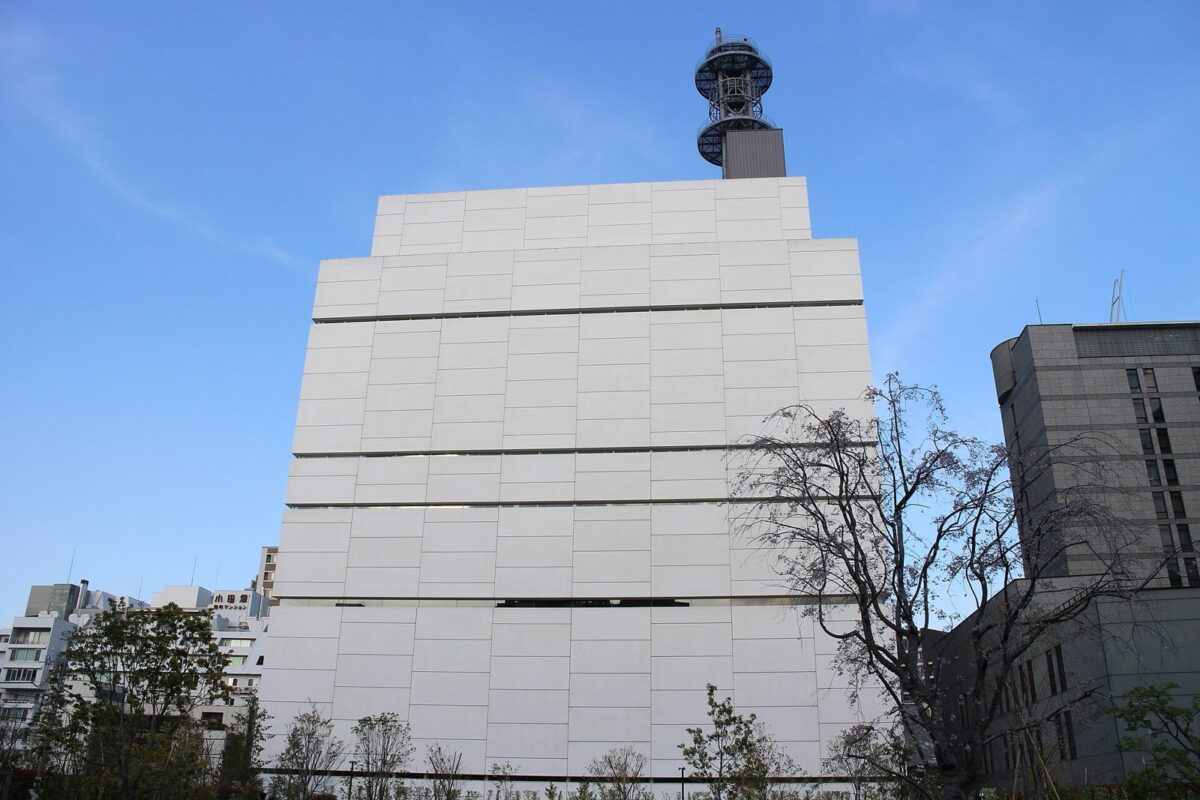 青空の下に建つ、白いパネルで覆われた大きな四角い建物の日本テレビ番町スタジオ。屋上にアンテナの塔が立つ