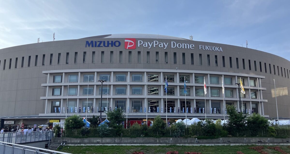 青空の下に立つ、円い大きなドーム球場。壁に「MIZUHO PayPay Dome FUKUOKA」の文字があり、手前の広場に人が集まっている