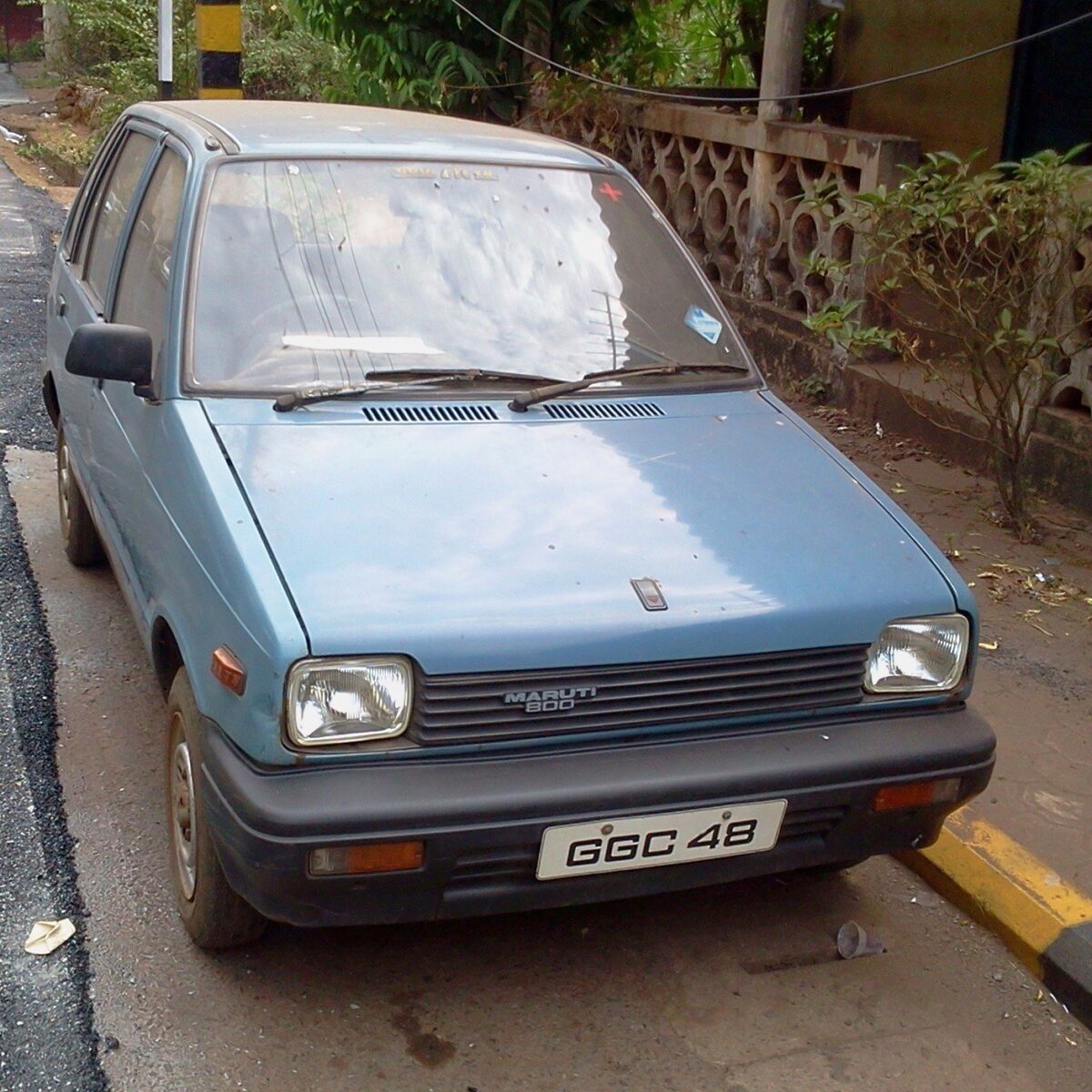 インドの町の道ばたに止まっている、水色の小さな古い車。前に「MARUTI 800」の文字