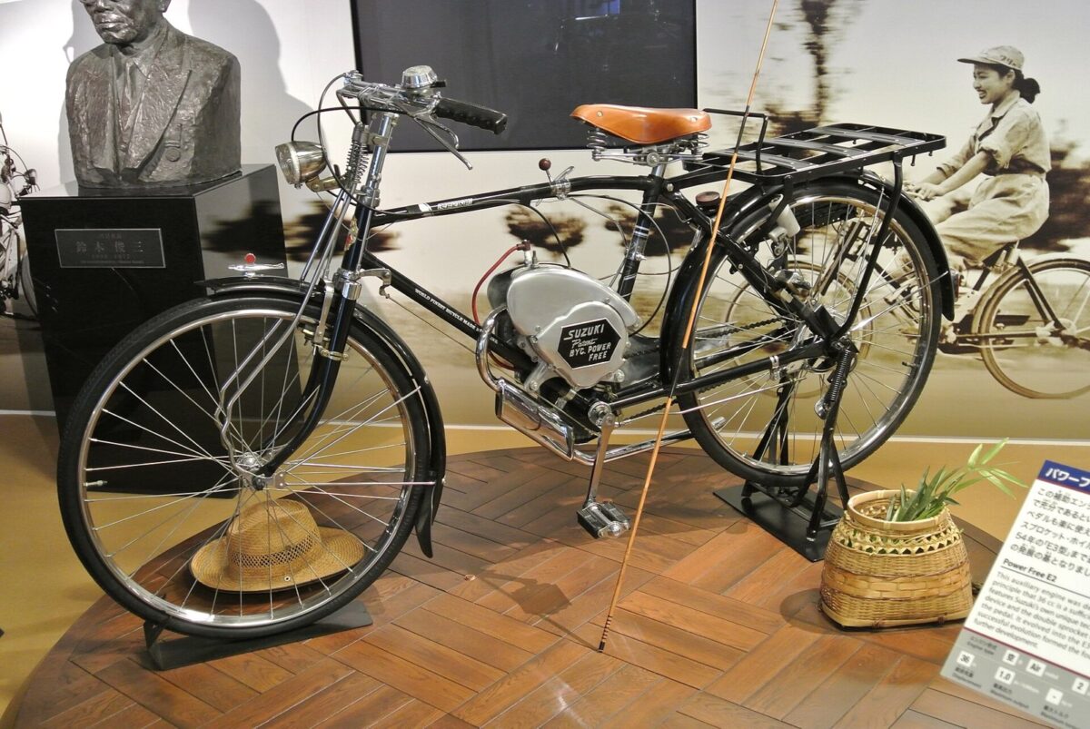 博物館に展示された、黒い自転車の車体の真ん中に小さなエンジンを付けた、古い乗り物
