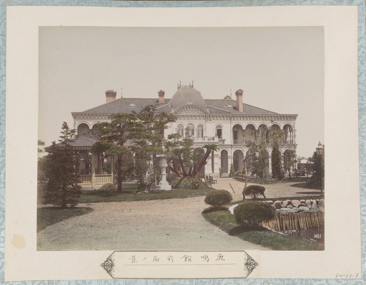 2階建ての白っぽい洋館を正面から写した古い白黒写真。1階と2階に、アーチの付いた窓と柱の並ぶベランダがある