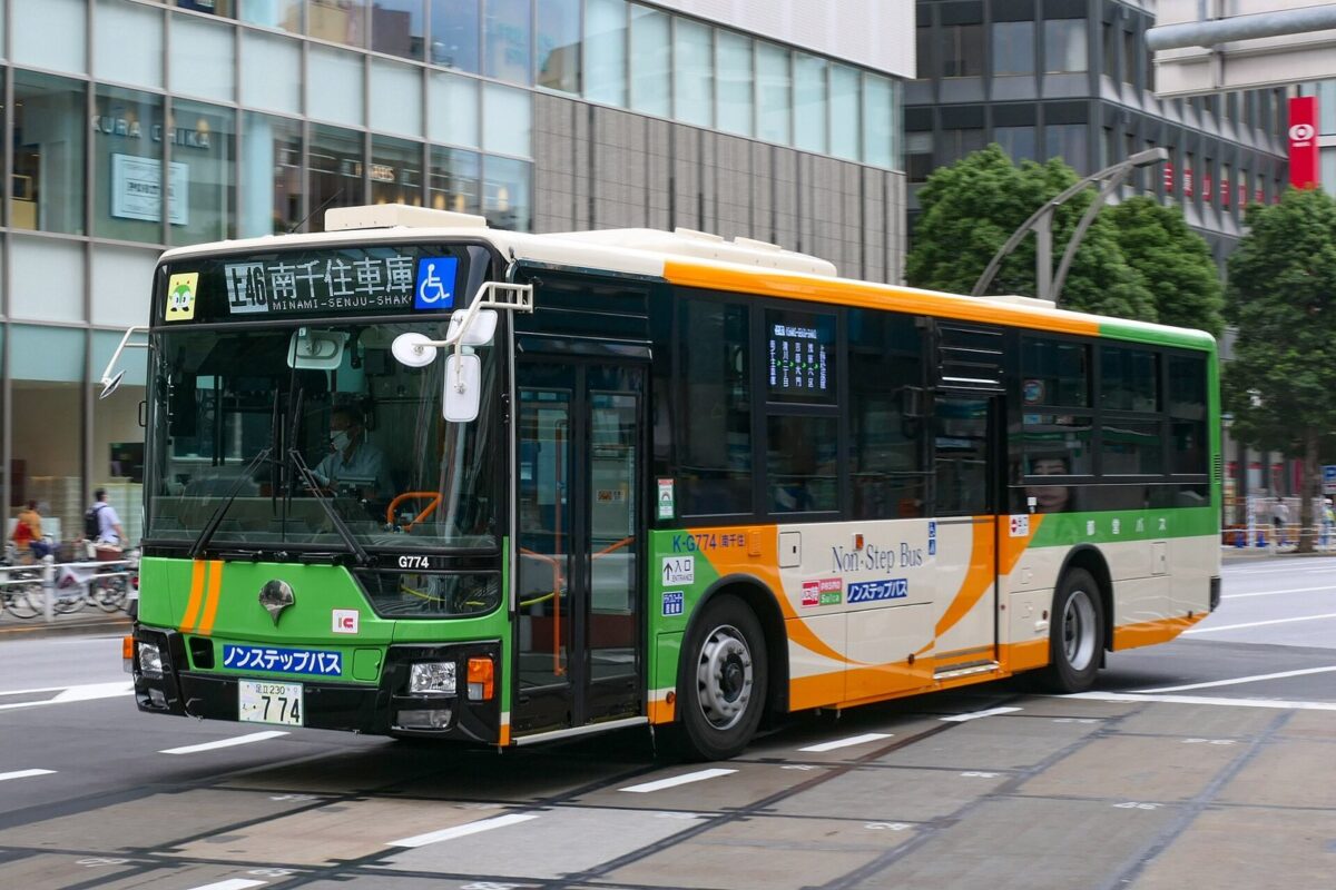 ビルの並ぶ通りを、緑とクリーム色に塗り分けた都営バスが走っている